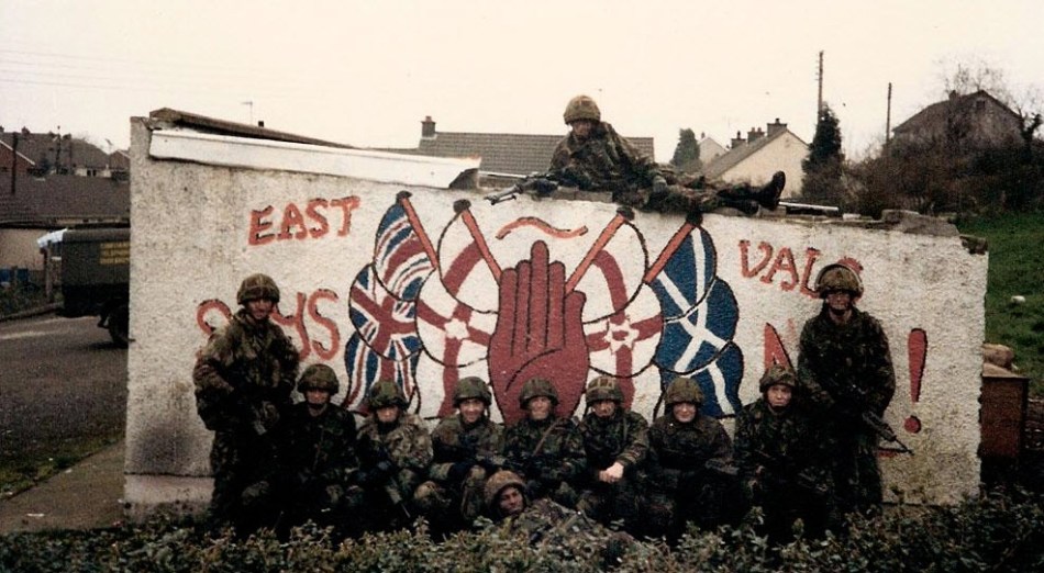 British Troops pose for a photo in front of a wall mural celebrating the British terror gangs in the north-east of Ireland, 1990s
