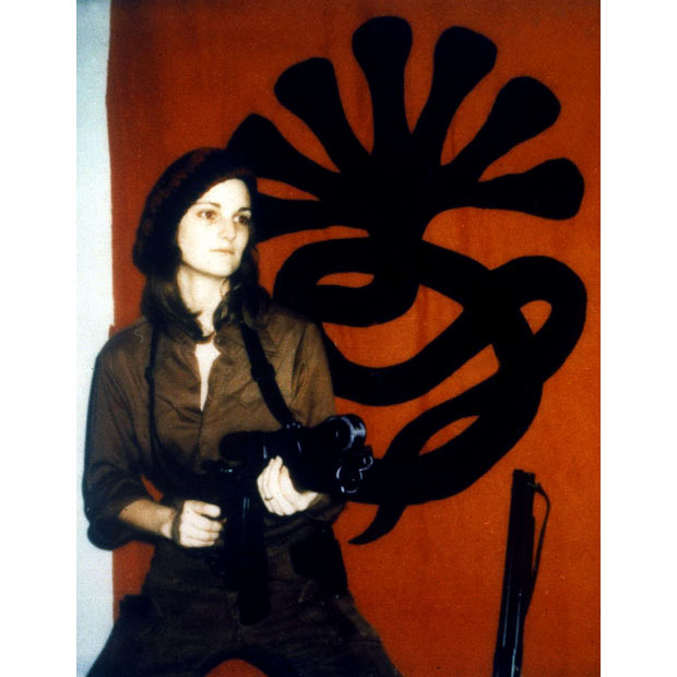 Patty Hearst in front of the insignia of the Symbionese Liberation Army (SLA)