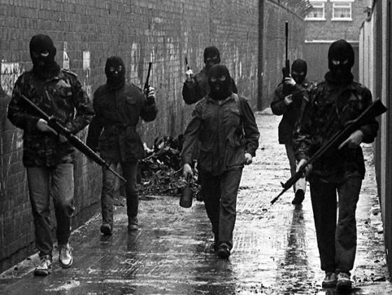 An Active Service Unit of the Irish Republican Army moves through Belfast, the Volunteer in the middle holding an anti-armour “drogue grenade”, British Occupied North of Ireland, c.1980s