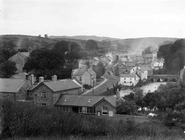 The main street of Pettigo, with the bridge into the village on the top right, and the train station to the fore, c.1900